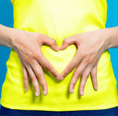 Woman with her hands in the shape of a heart over her stomach