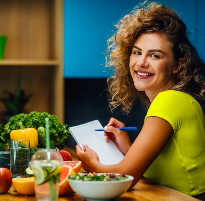 Eat Healthy | Woman in green shirt with fruit and vegetables around her